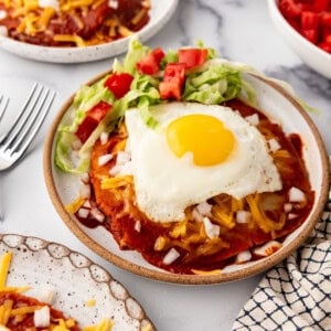 A plate of stacked enchiladas topped with a fried egg.