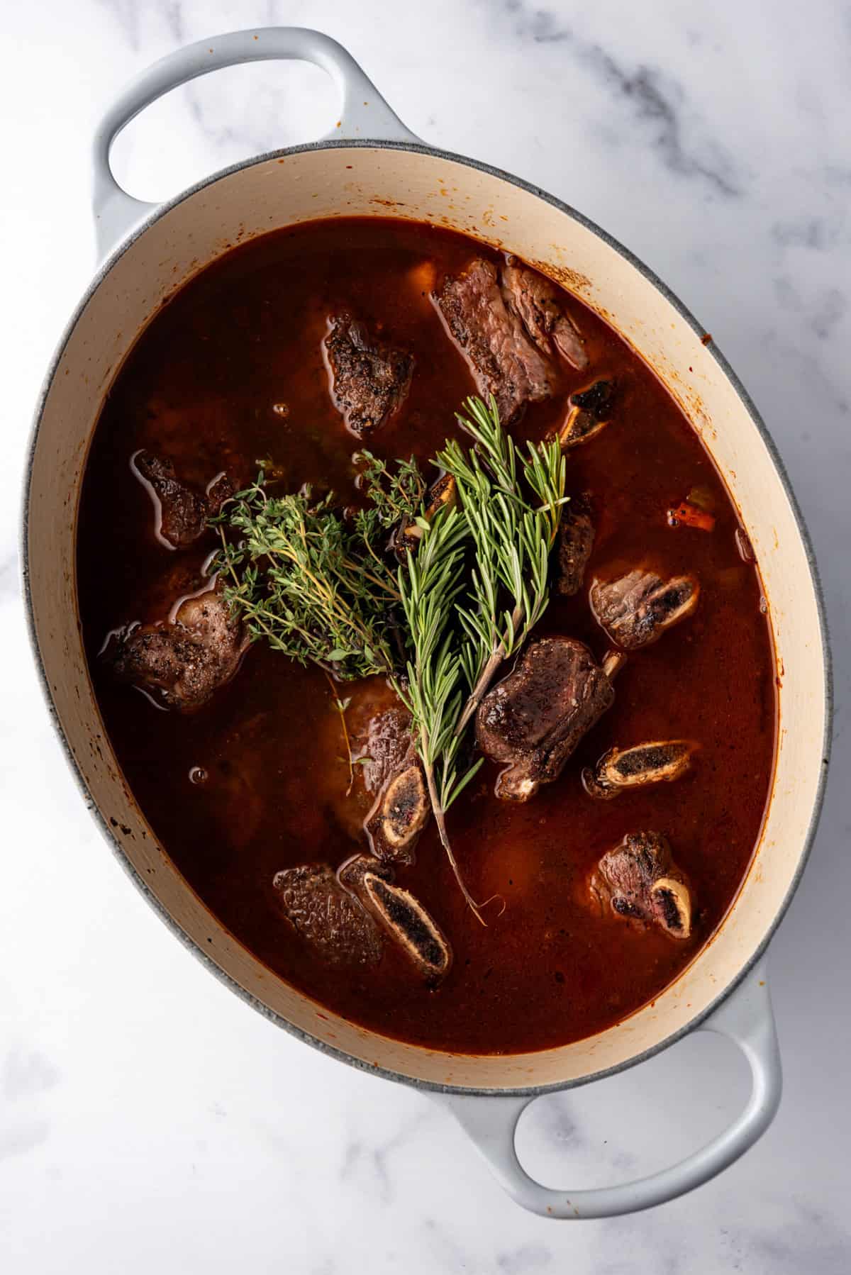 Overhead image of everything added to large dutch oven to make Braised Short Ribs, and ready to cook.