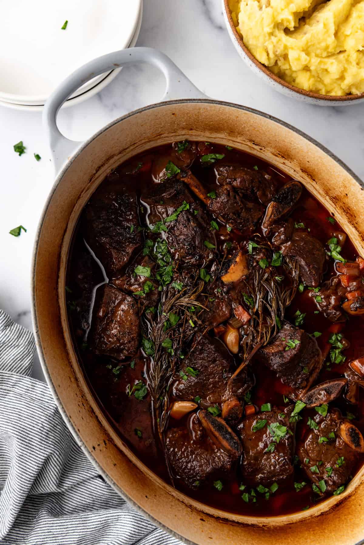 Overhead image of large dutch oven containing cooked Braised Short Ribs meal.