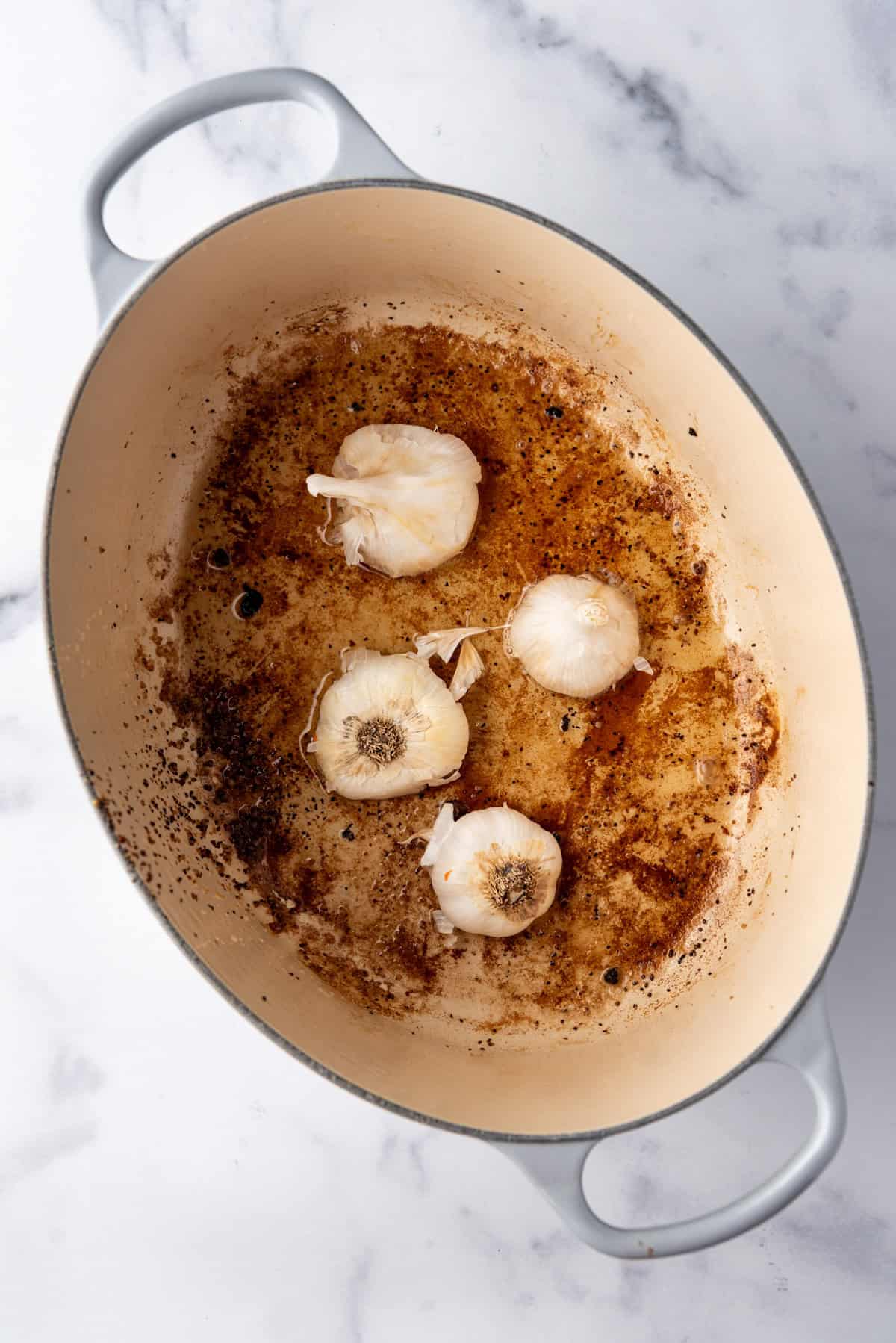 Overhead image of garlic added to large dutch oven.