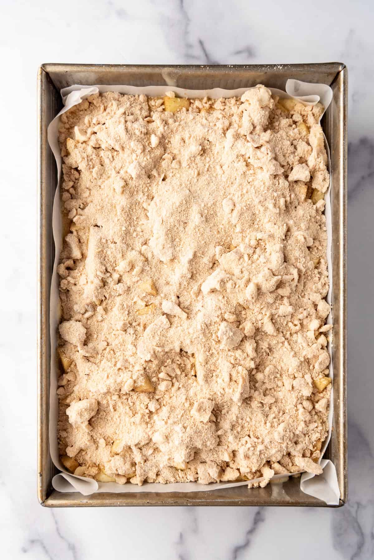 Overhead view of streusel topping sprinkled over the apple filling.