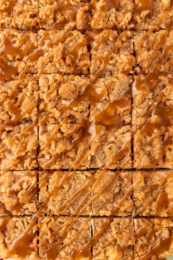 An overhead image of caramel apple cheesecake bars cut into squares with caramel drizzled over the top.