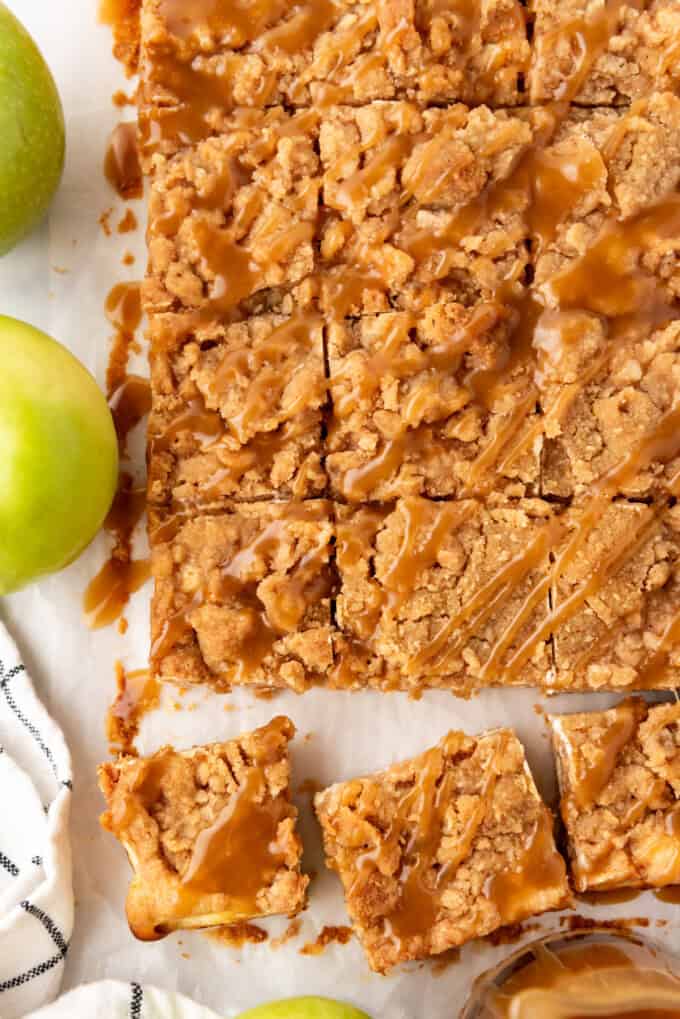 An overhead image of caramel apple cheesecake bars cut into squares with caramel drizzled over the top.