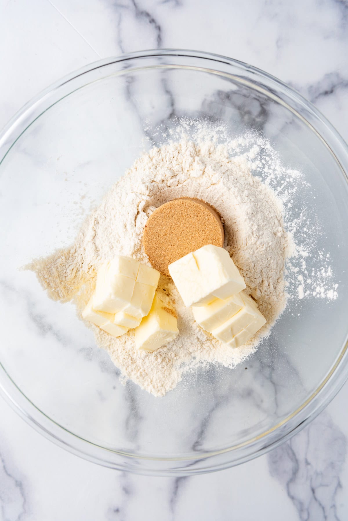 Overhead view of glass mixing bowl with flour, brown sugar, and salt in it.