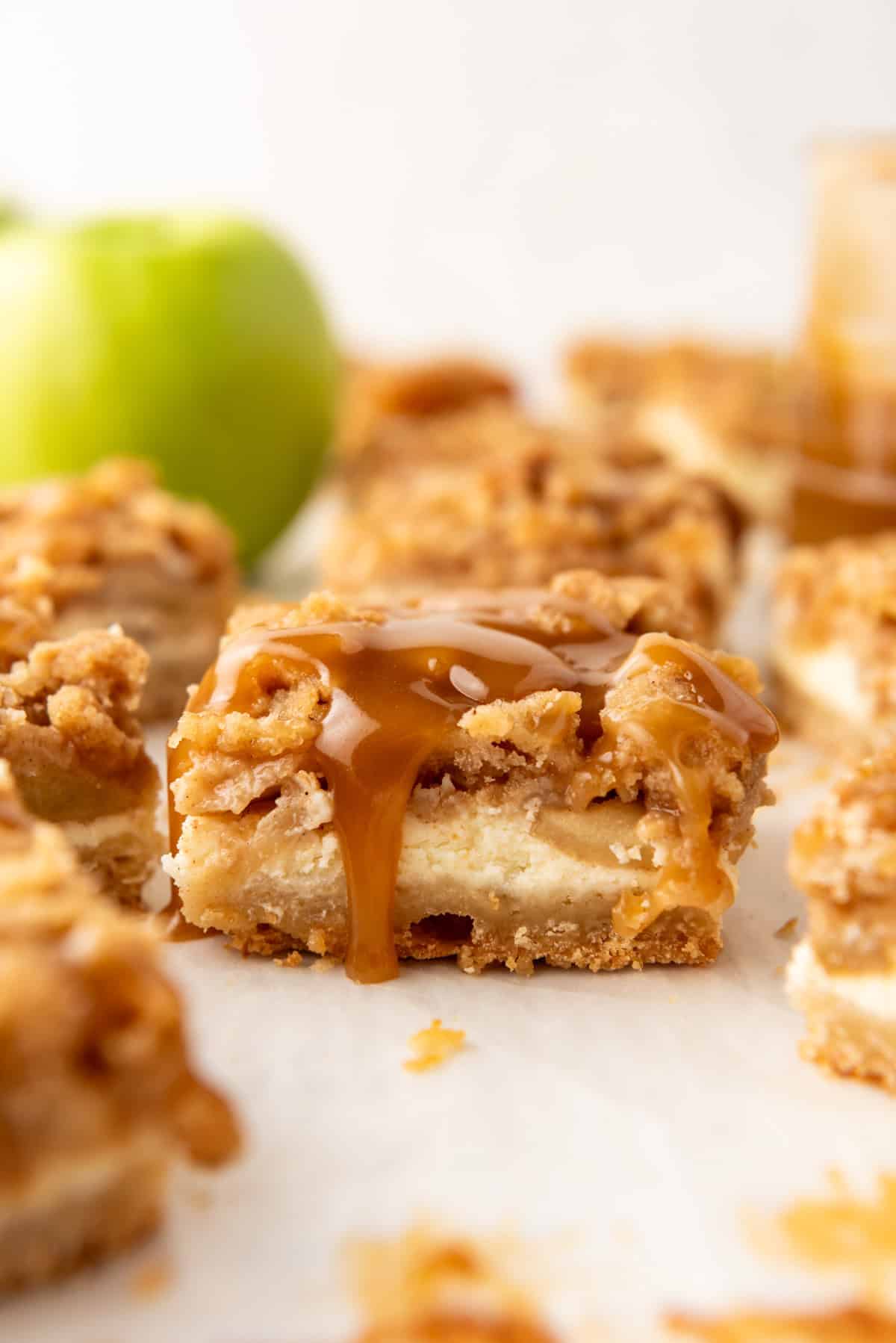 An image of a caramel apple cheesecake bar with caramel dripping down the side.