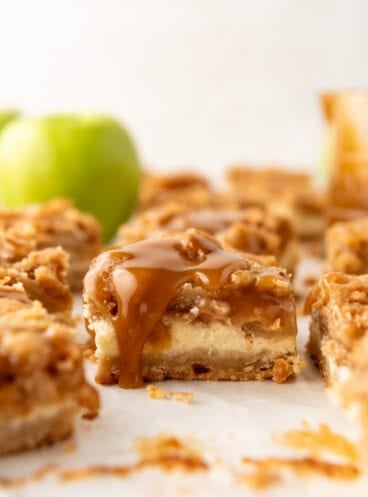 An image of a caramel apple cheesecake bar with caramel dripping down the side.