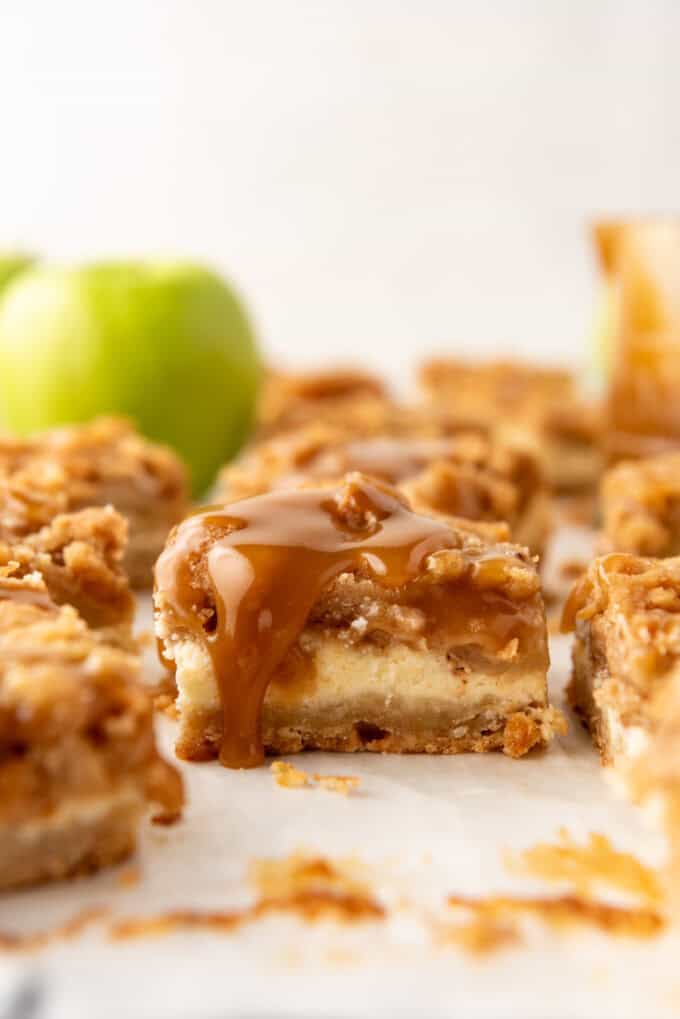 An image of a caramel apple cheesecake bar with caramel dripping down the side.