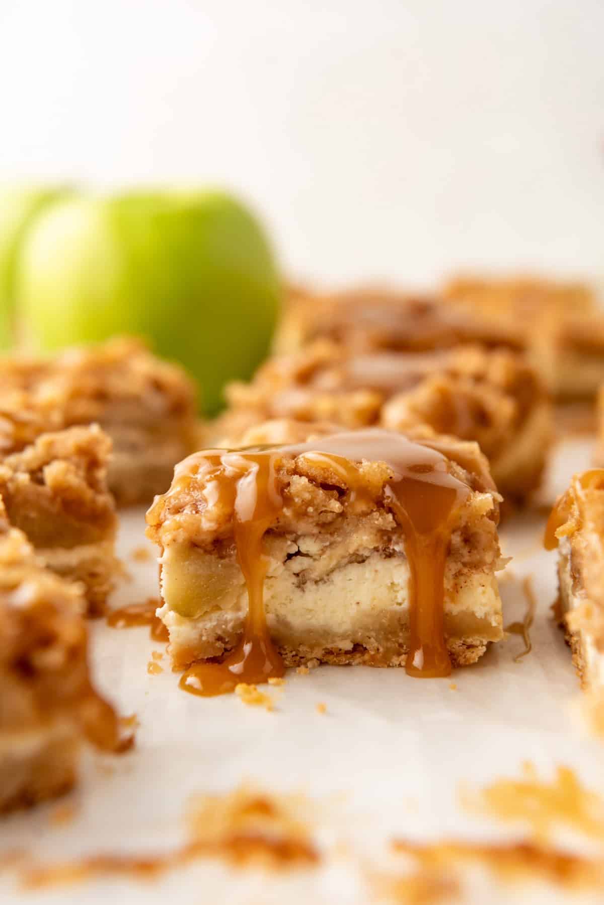 An image of a caramel apple cheesecake bar with caramel dripping down the side.