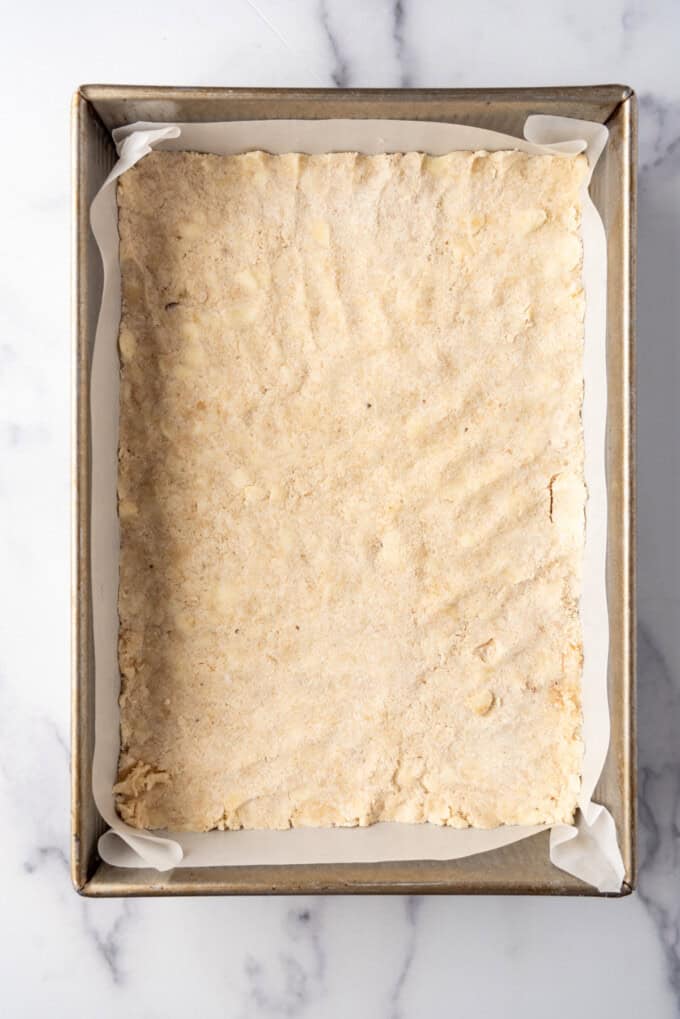 Overhead view of crust mixture pressed into a prepared 9x13-inch pan.