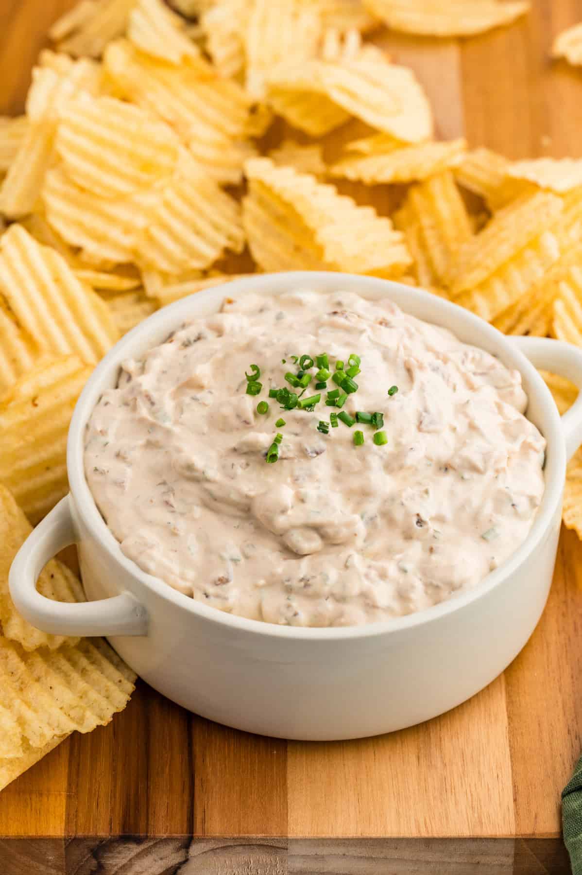 A bowl of homemade french onion dip with chopped chives sprinkled on top.