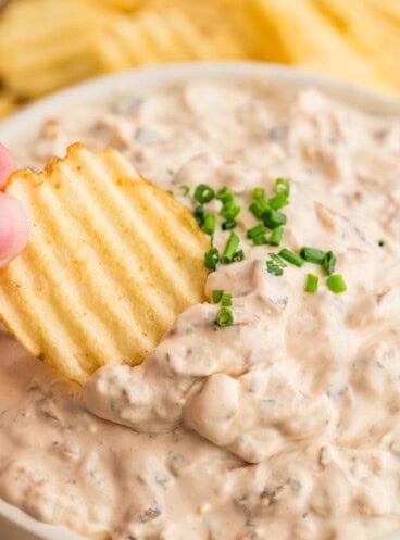 A chip being used to scoop up french onion dip.