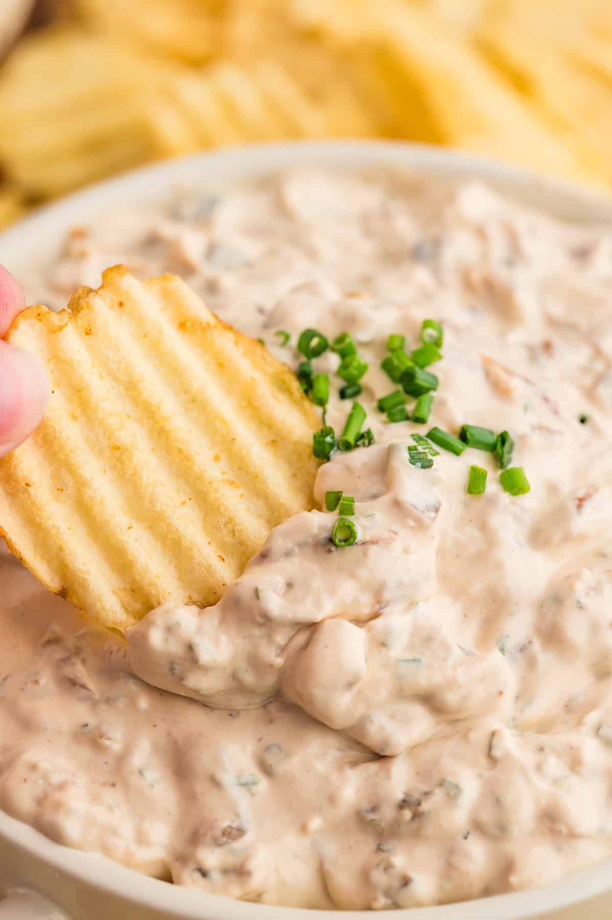 A chip being used to scoop  up french onion dip.