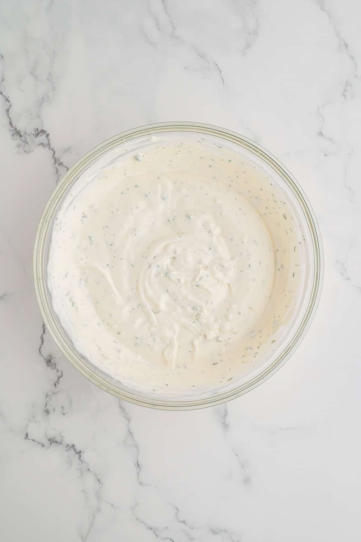 Whisked dip ingredients in a glass mixing bowl.