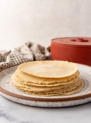 An image of homemade corn tortillas stacked on a plate.