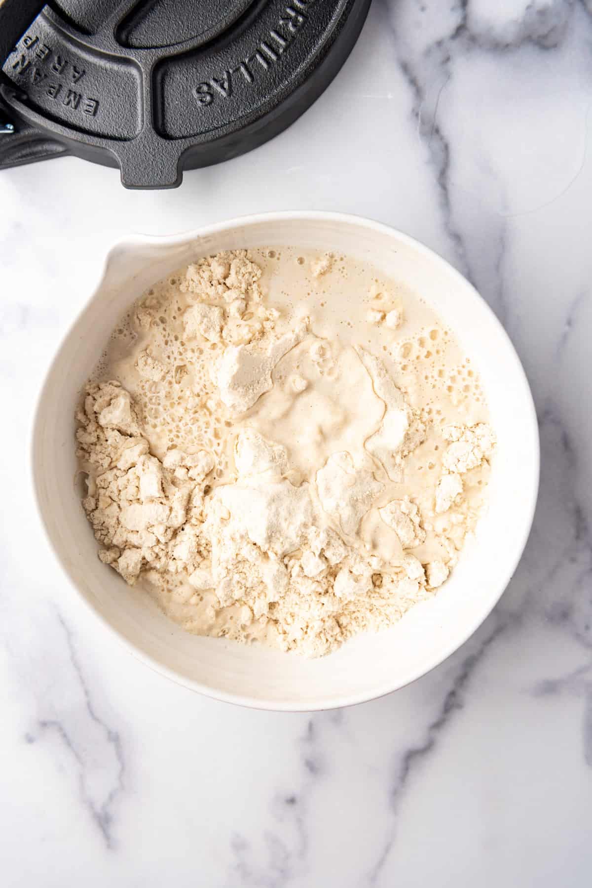 Adding water to masa flour in a bowl.