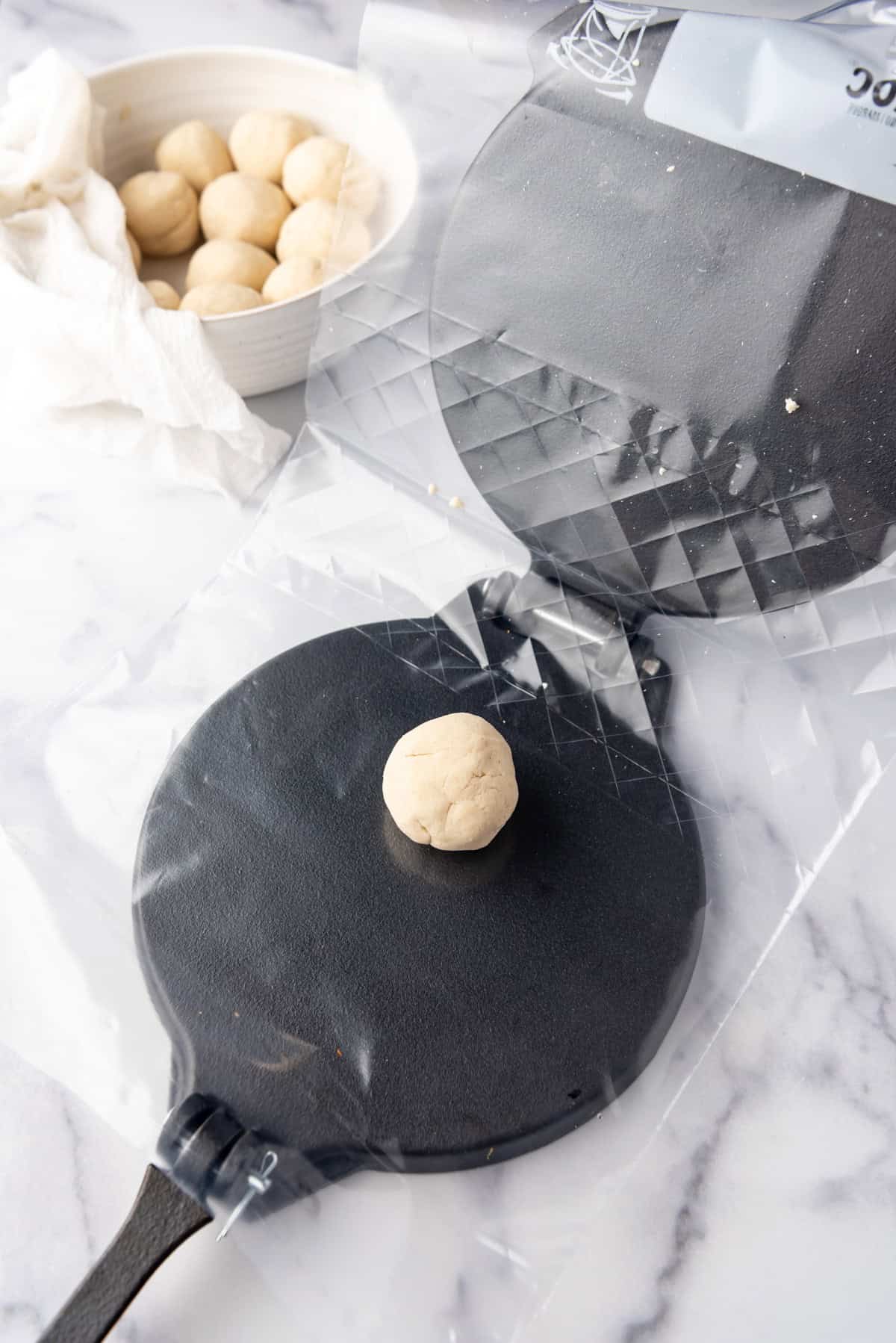 A ball of corn tortilla dough on a tortilla press.