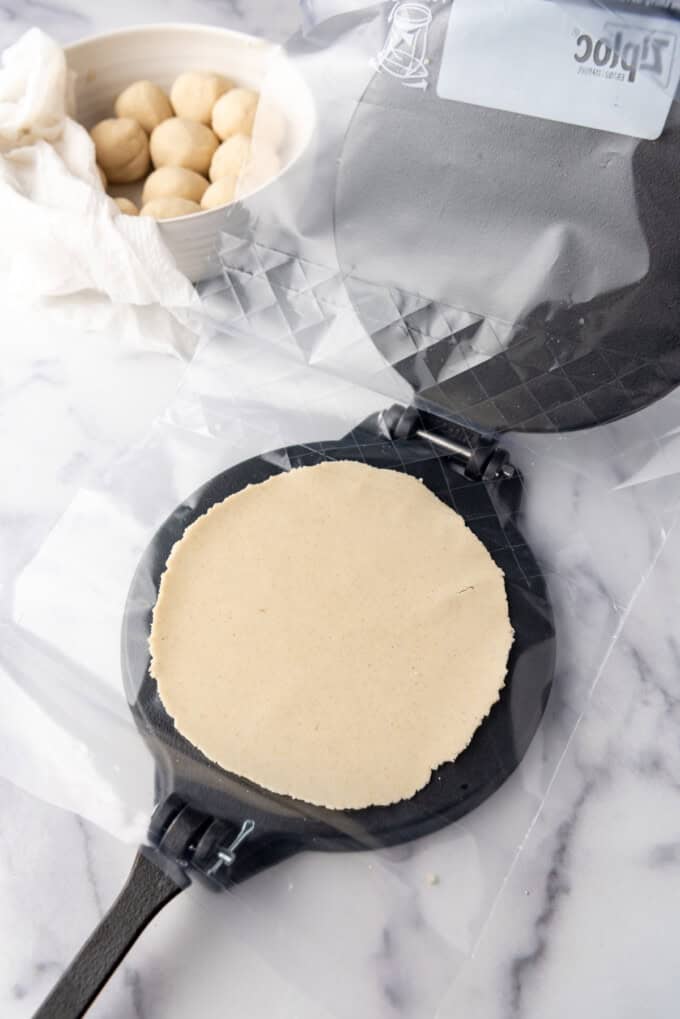 Une tortilla de maïs dans un presse-tortilla.