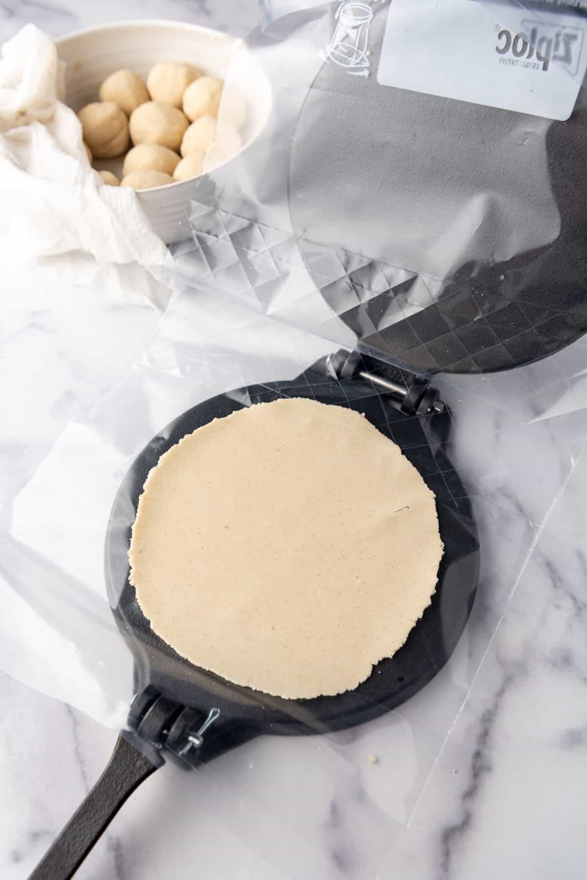 A corn tortilla in a tortilla press.