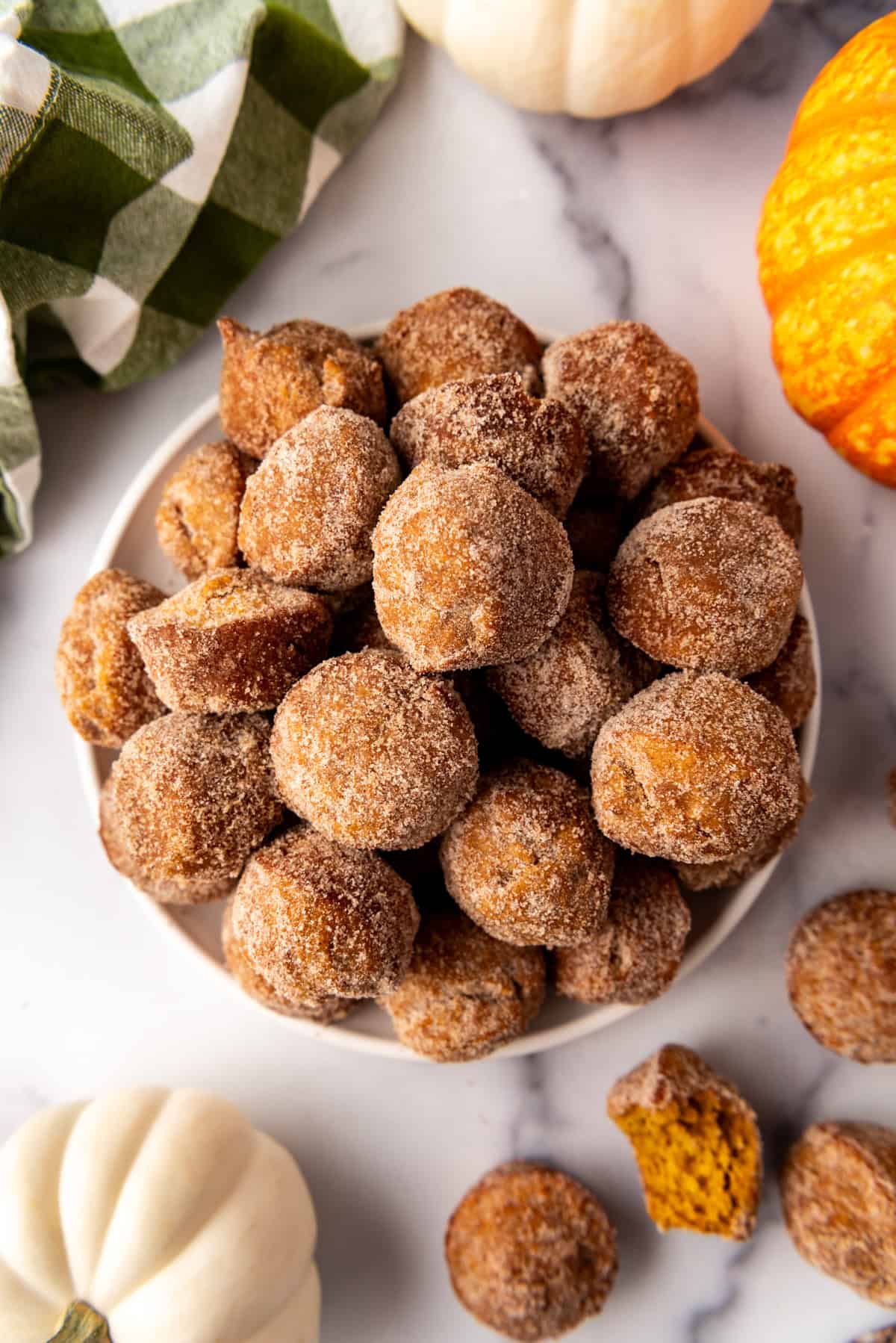 An overhead image of a plate piled with mini pumpkin donut muffins. 