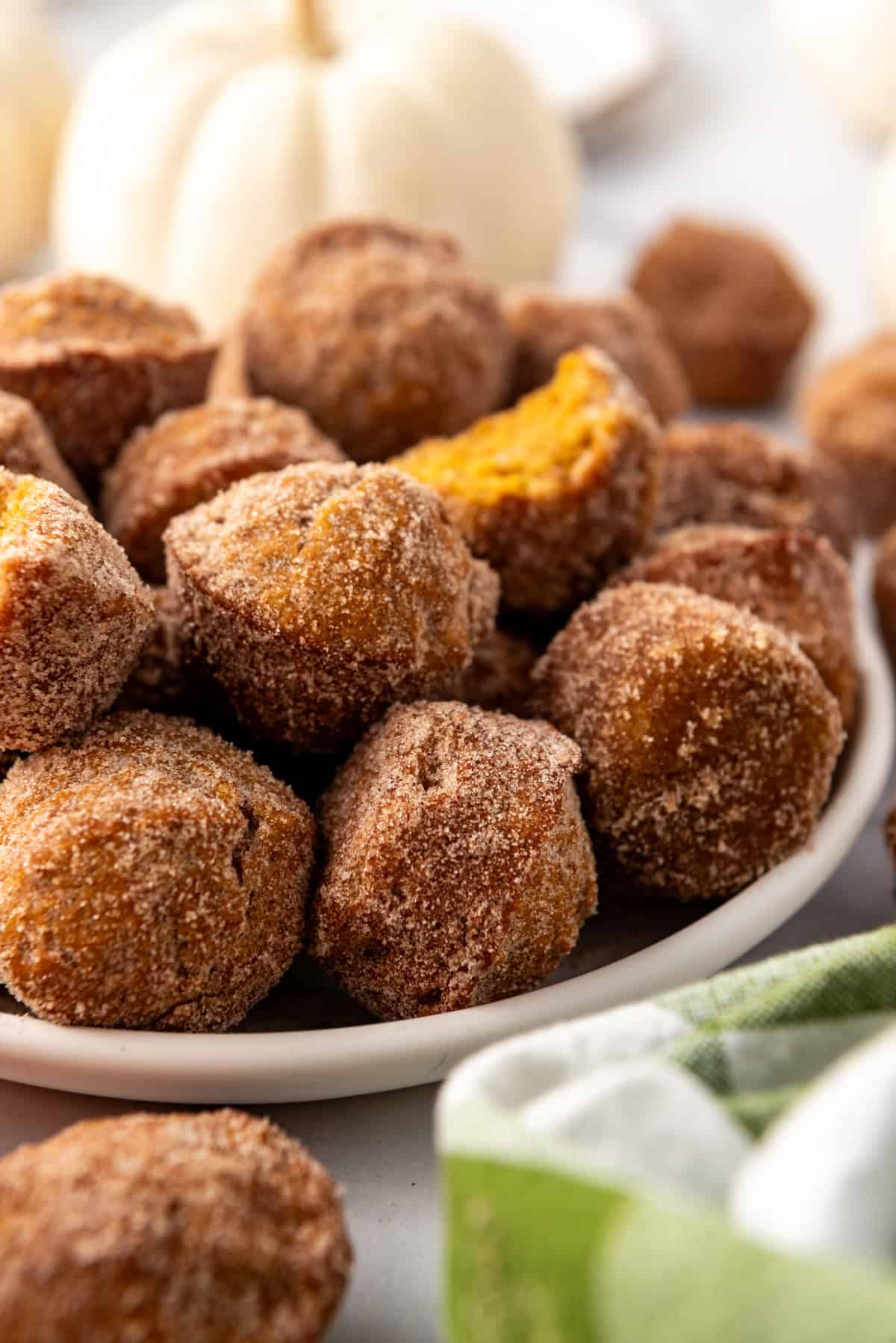 Bite-size pumpkin muffins on a plate in front of a white pumpkin.