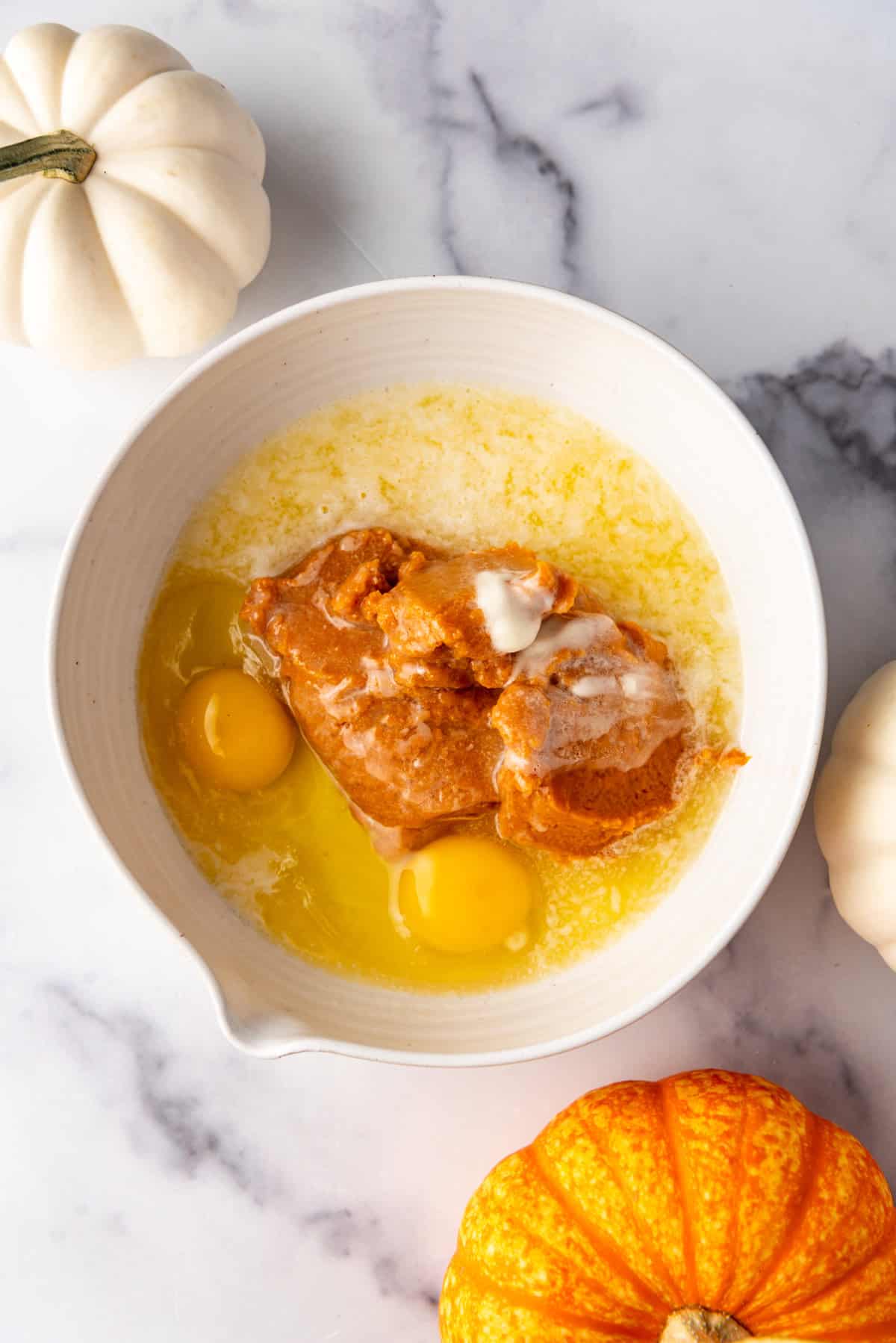 Combining wet ingredients for pumpkin muffins in a mixing bowl.