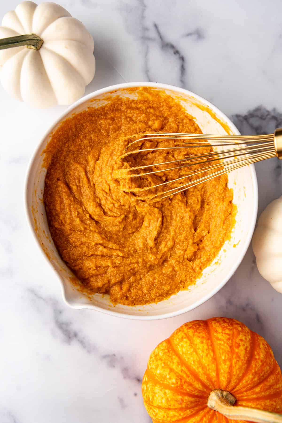 Whisked wet pumpkin ingredients in a bowl for making muffins.