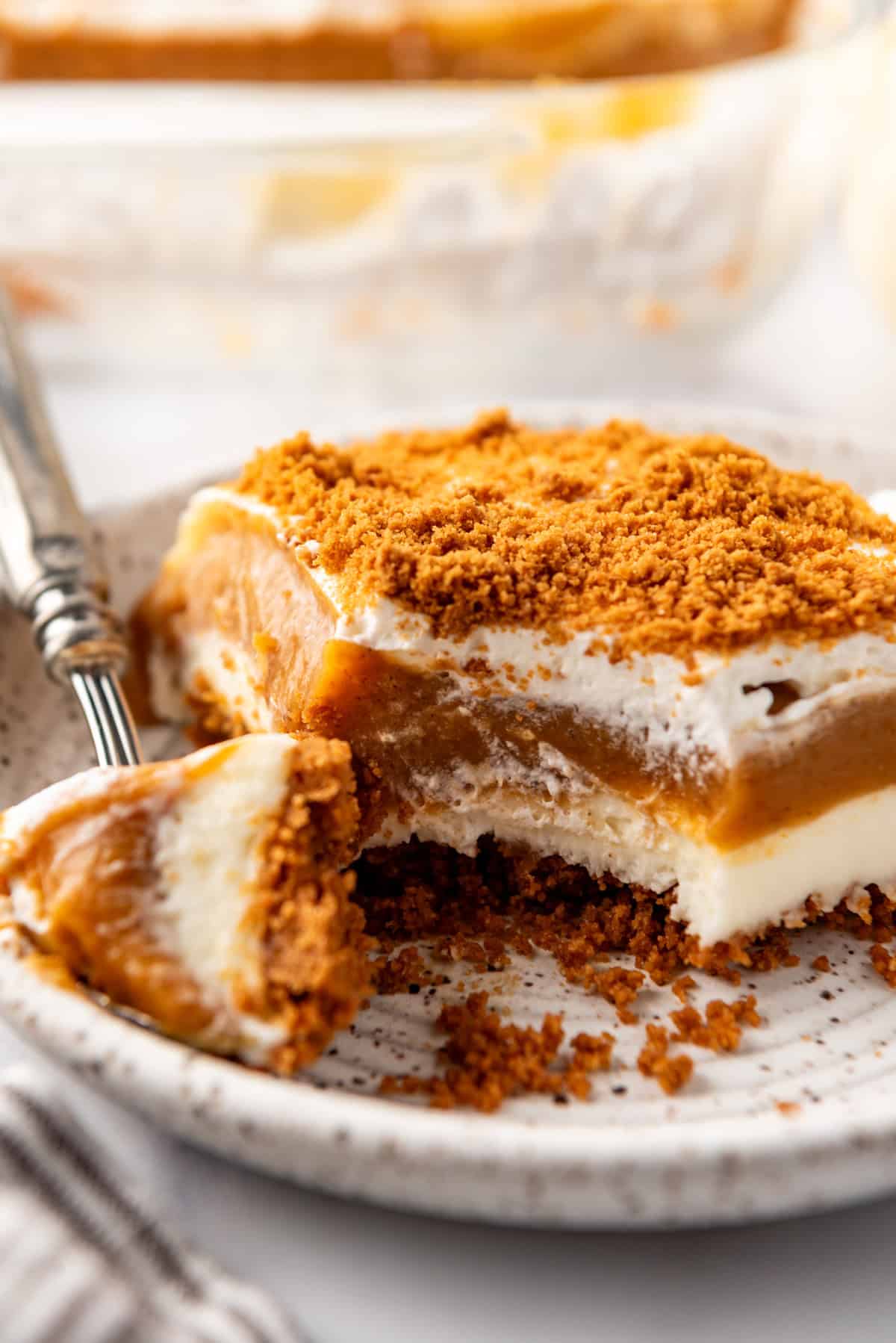 A close up image of a serving of layered pumpkin delight with a bite taken out of it.