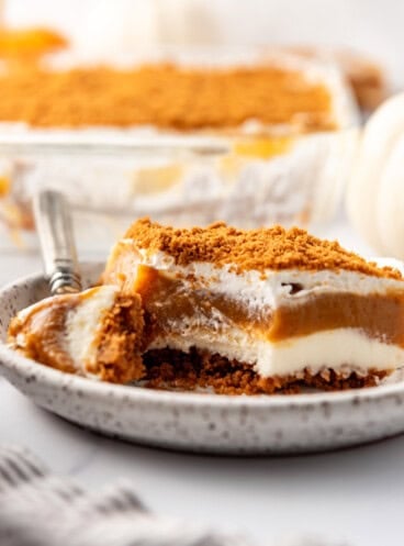 A slice of pumpkin delight on a plate with a spoonful of dessert on it.