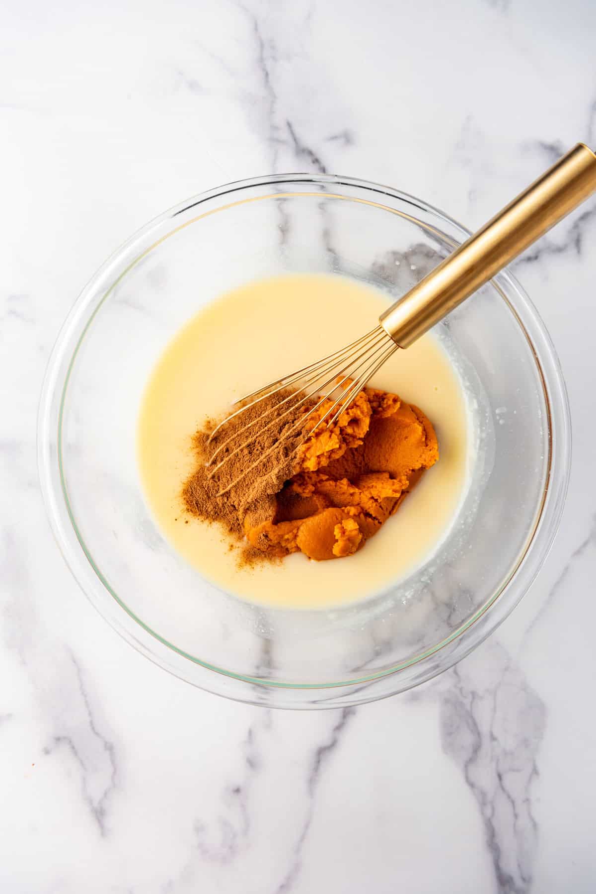 Whisking pumpkin and spices into pudding in a bowl.