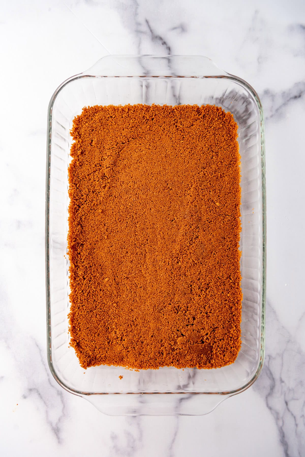 A biscoff crust pressed into a 9x13-inch baking dish.