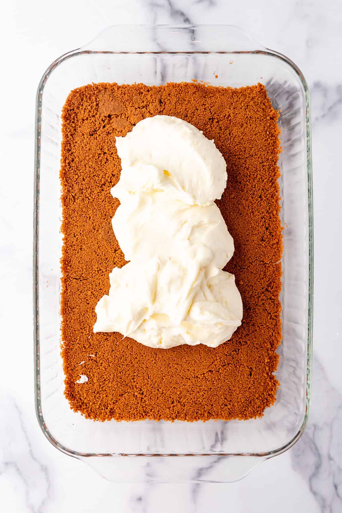 Adding a layer of cream cheese filling on top of a biscoff crust.