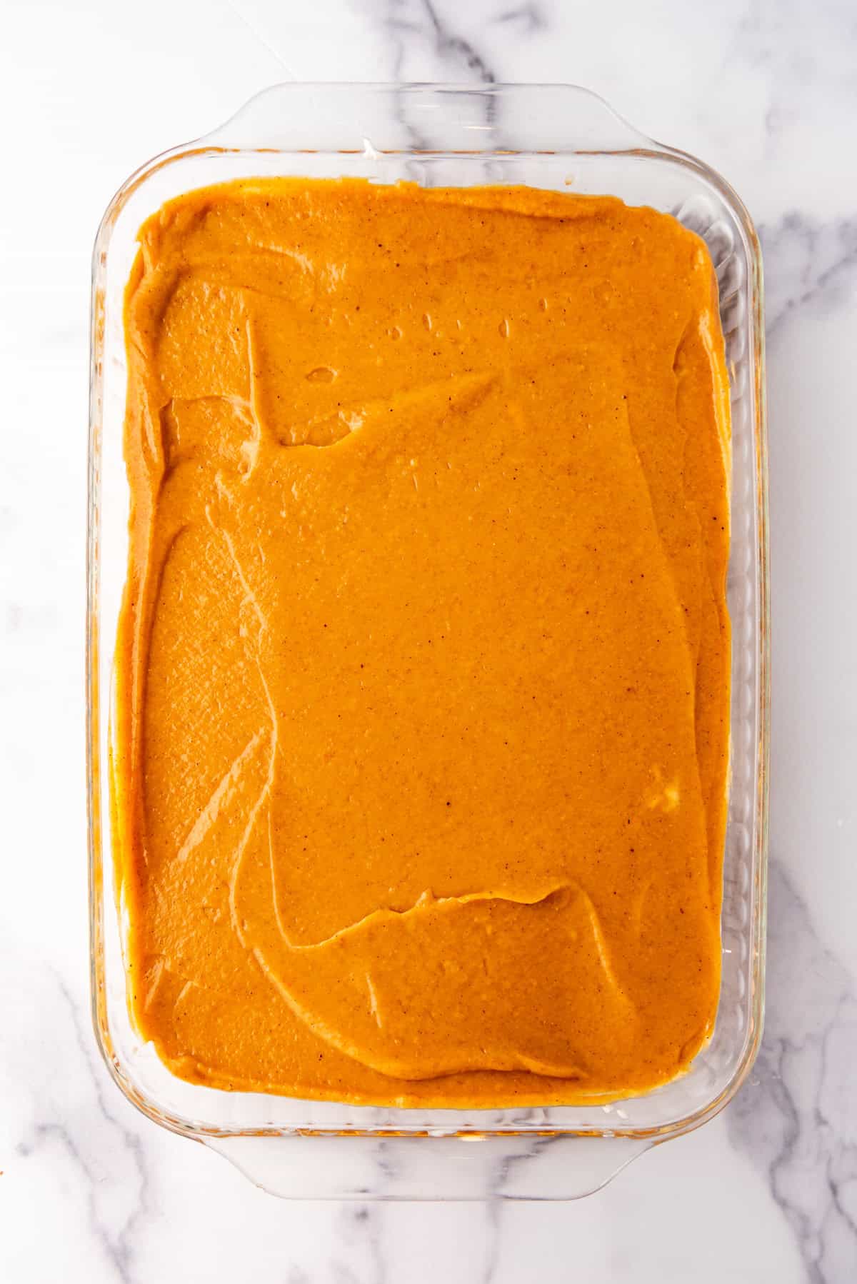 Spreading a layer of no-bake pumpkin filling in a dessert pan.