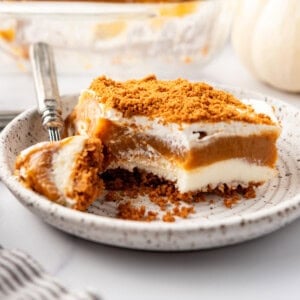 A close up image of a serving of layered pumpkin delight with a bite taken out of it.