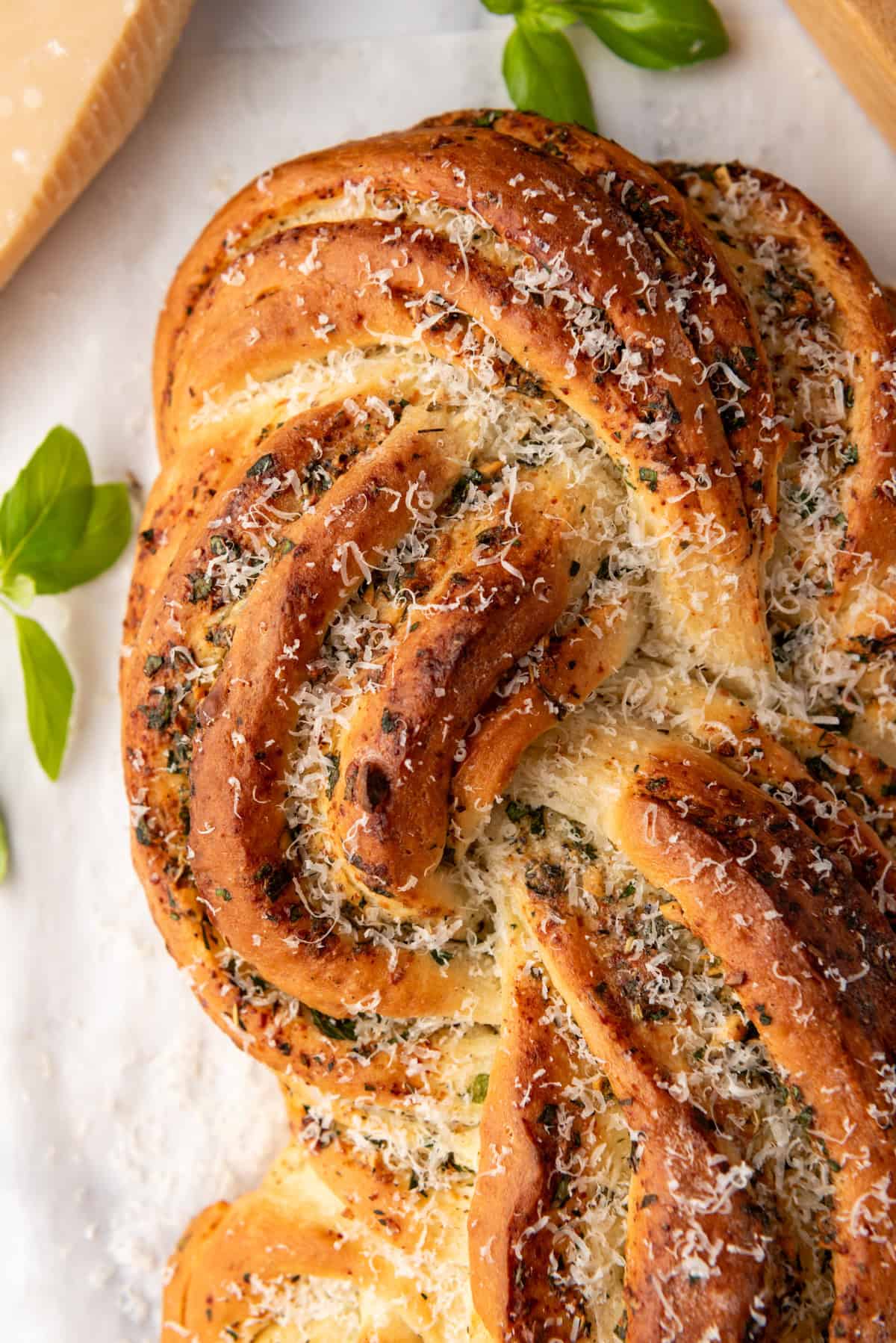 A close up image of a loaf of swirled garlic herb bread sprinkled with parmesan cheese.