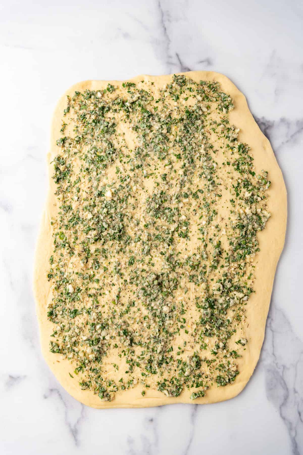 Bread dough spread with a garlic herb butter spread.