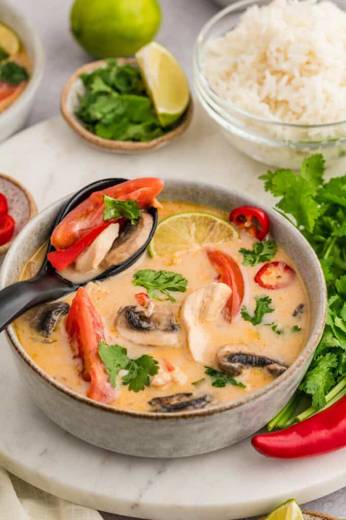 A spoonful of Thai coconut chicken soup resting on the side of the bowl.