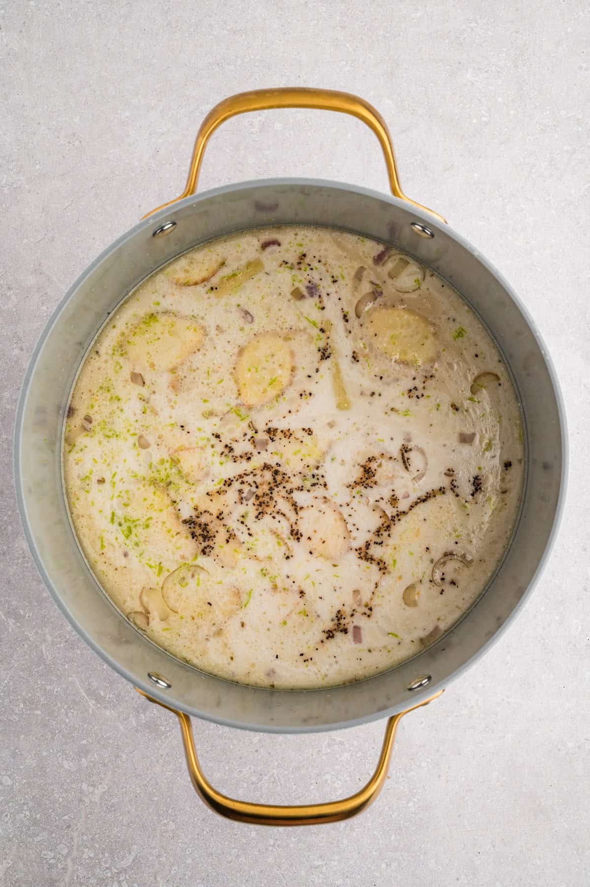 Adding coconut milk, sliced ginger, and other ingredients to make tom kha gai soup.