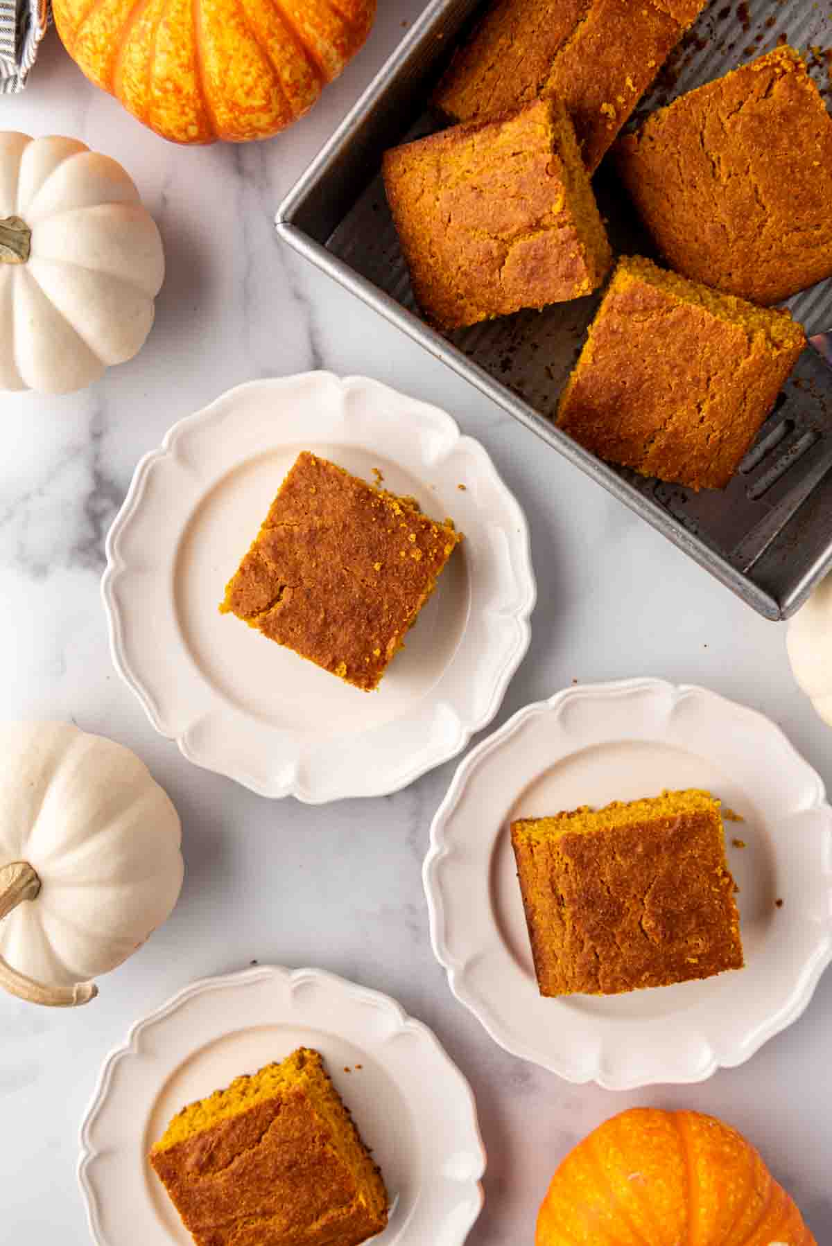 Carrés de pain de maïs à la citrouille sur des assiettes.