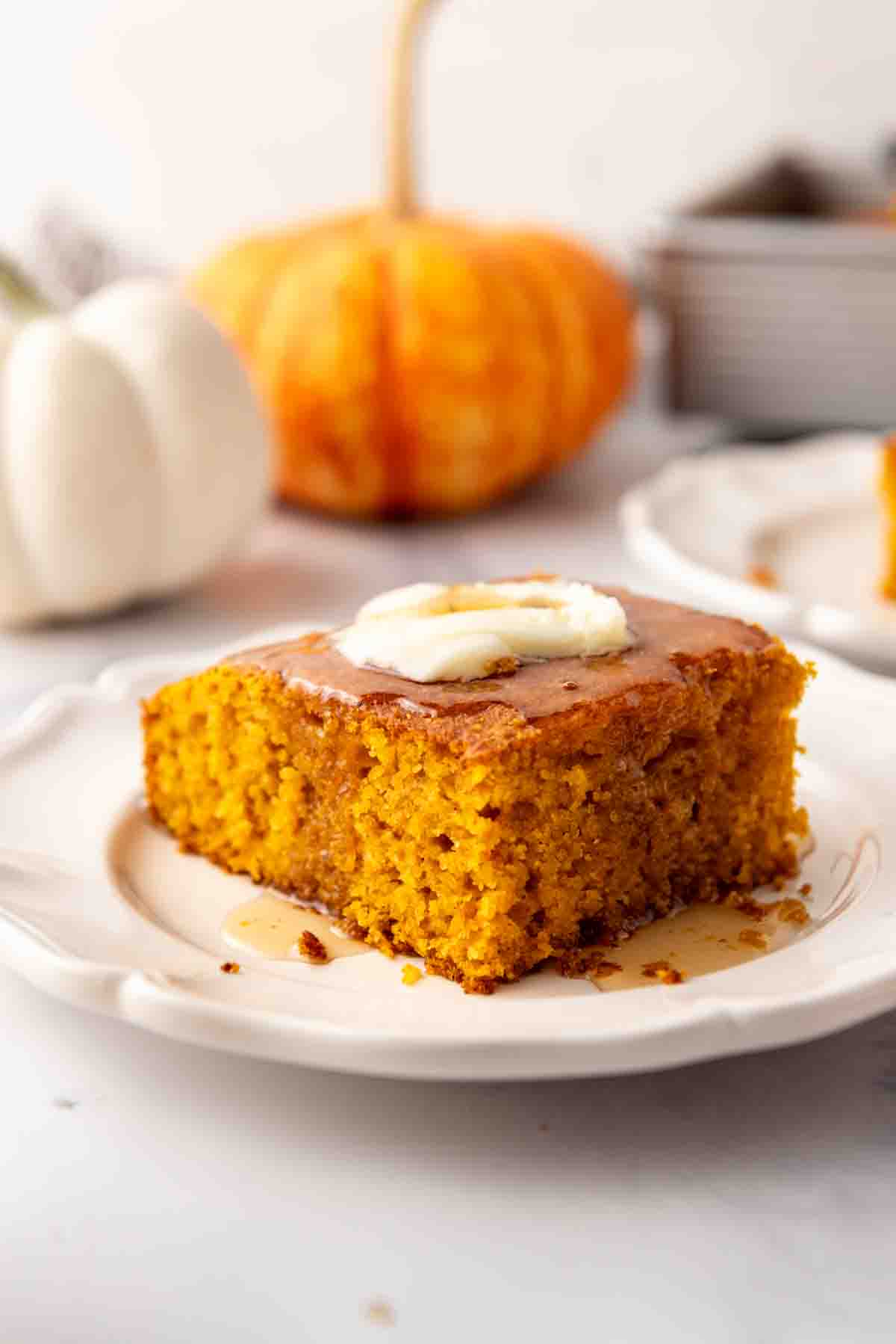 A slice of pumpkin cornbread on a plate with butter and honey on top.