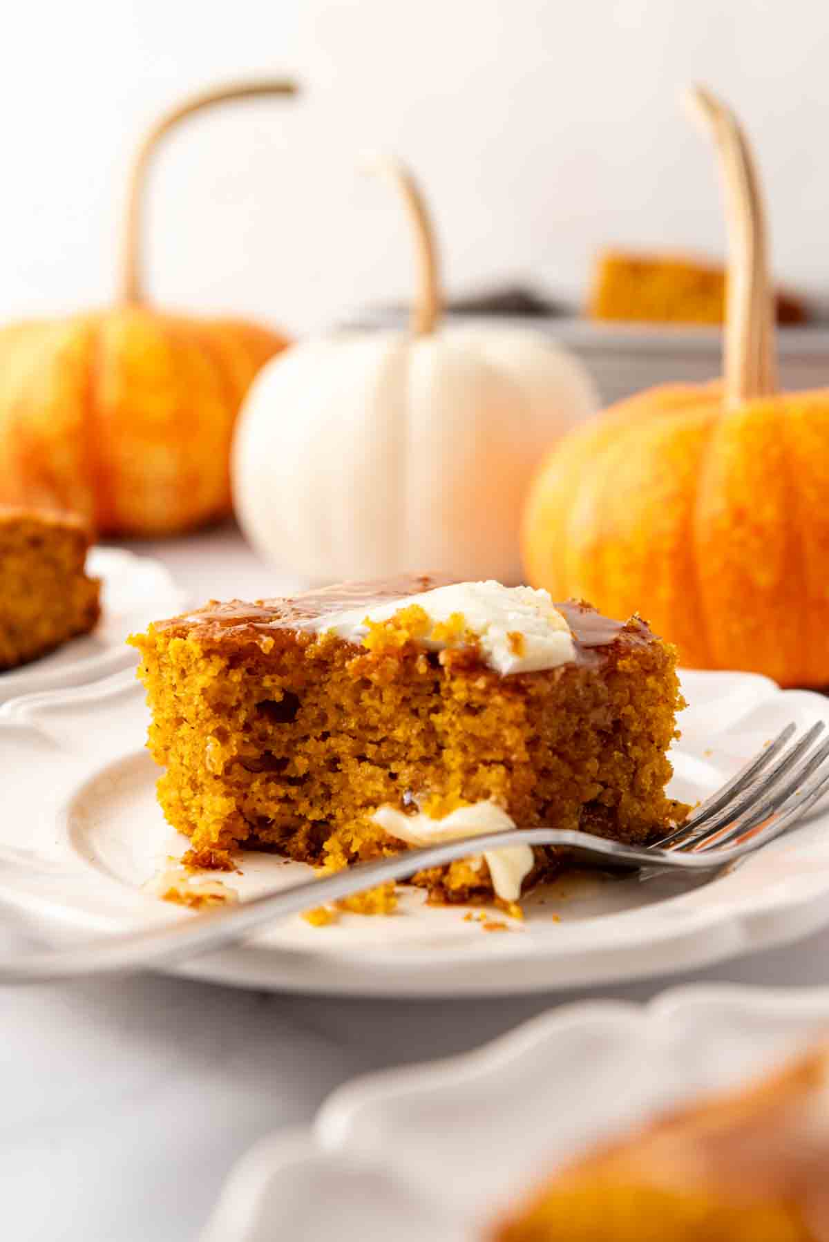 A piece of pumpkin cornbread on a plate with a fork and a bite taken out of the cornbread.