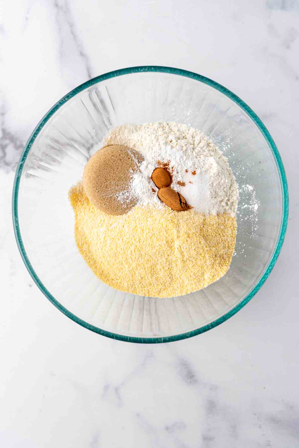 Dry ingredients for cornbread in a glass mixing bowl.