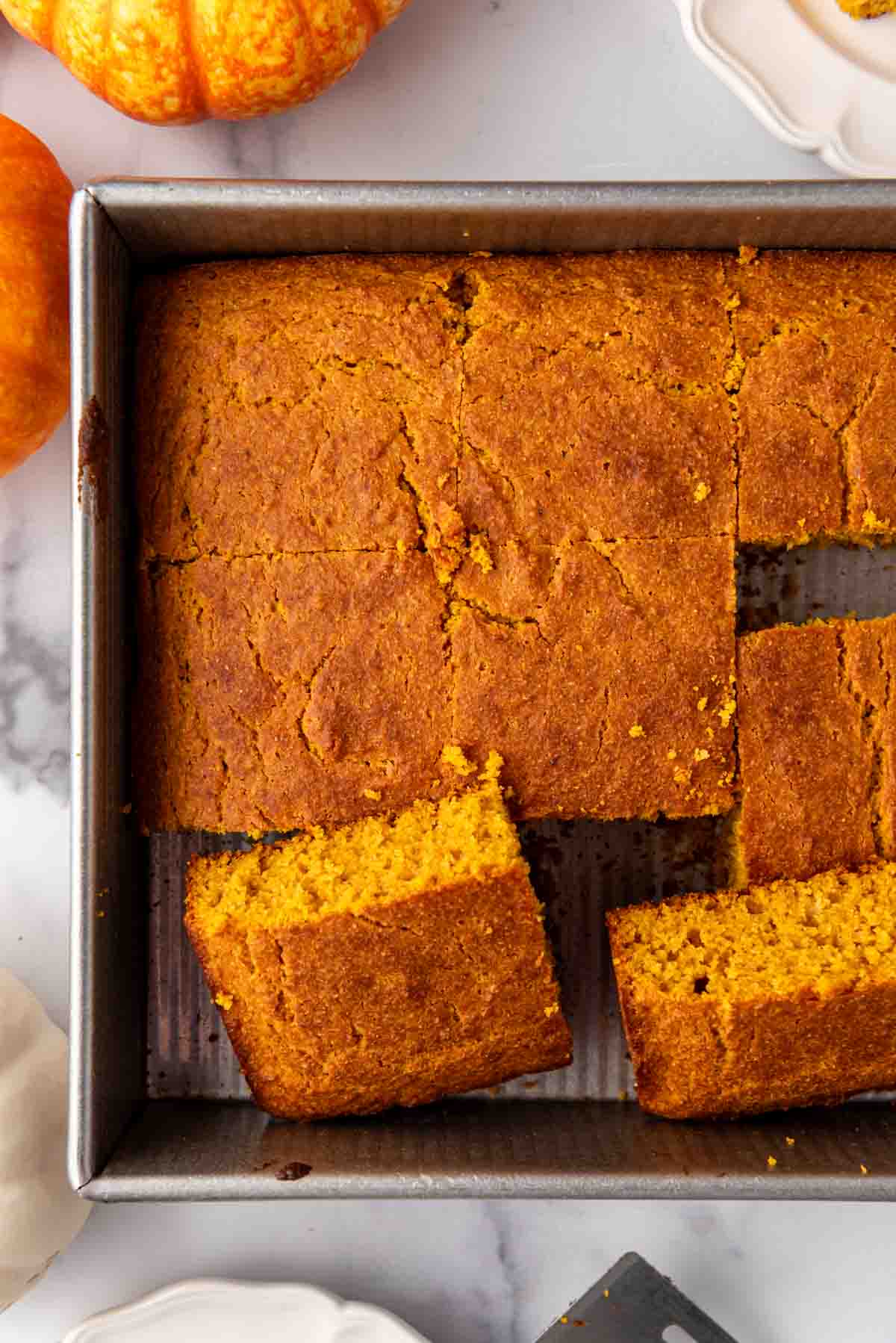 An overhead image of pieces of sliced pumpkin cornbread in a baking pan.