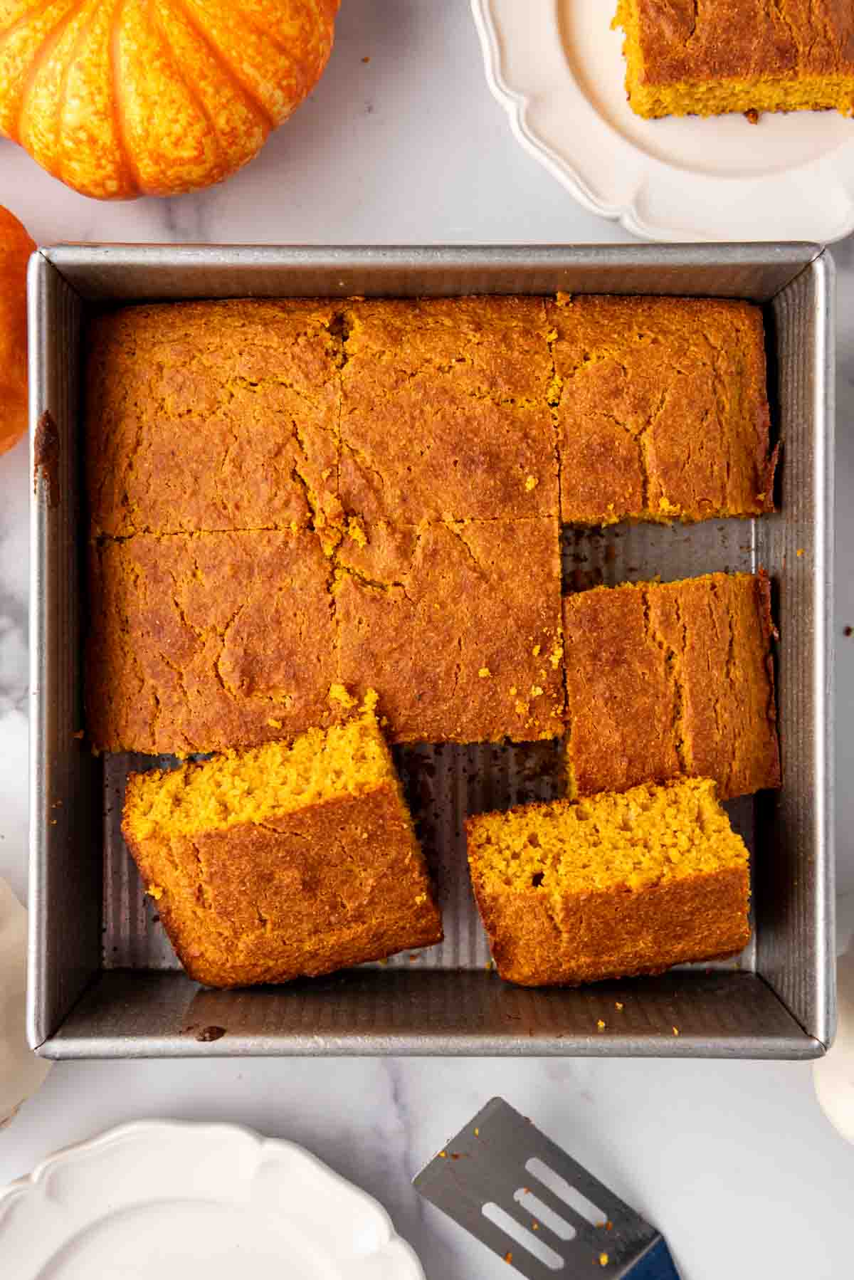 A pan of moist pumpkin cornbread that has been cut into squares.