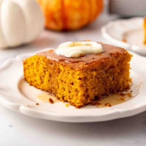 A slice of pumpkin cornbread on a plate with butter and honey on top.