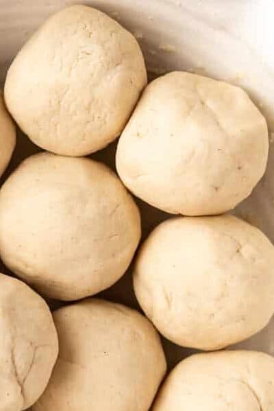 A bowl of balls of corn tortilla dough covered with a damp paper towel.