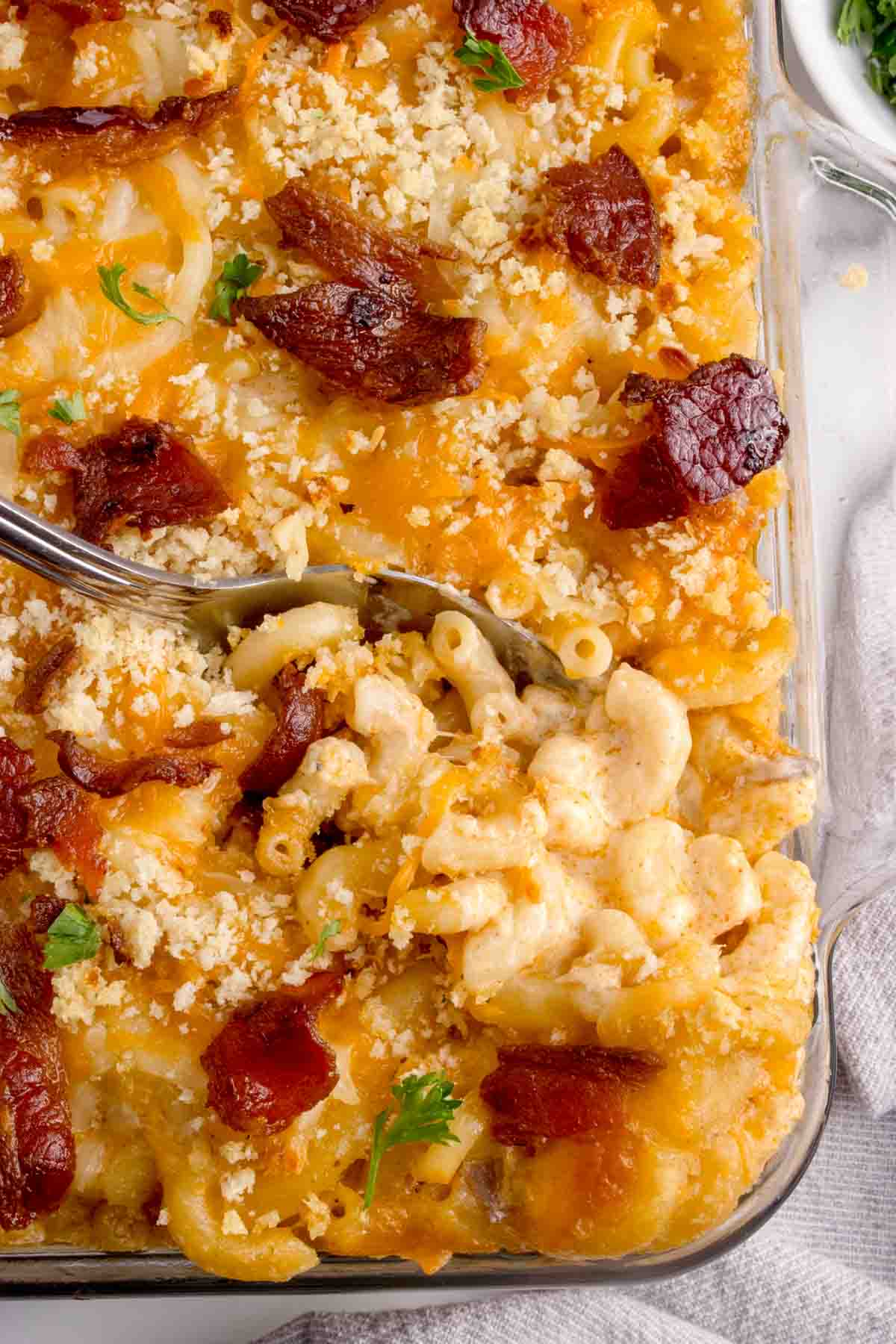 A close up image of a spoon in a pan of lobster mac and cheese.