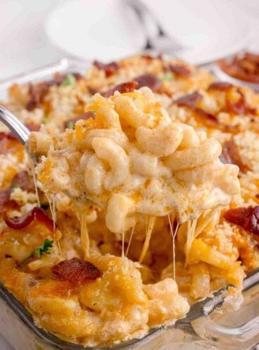 A spoonful of lobster mac and cheese being lifted out of the pan.