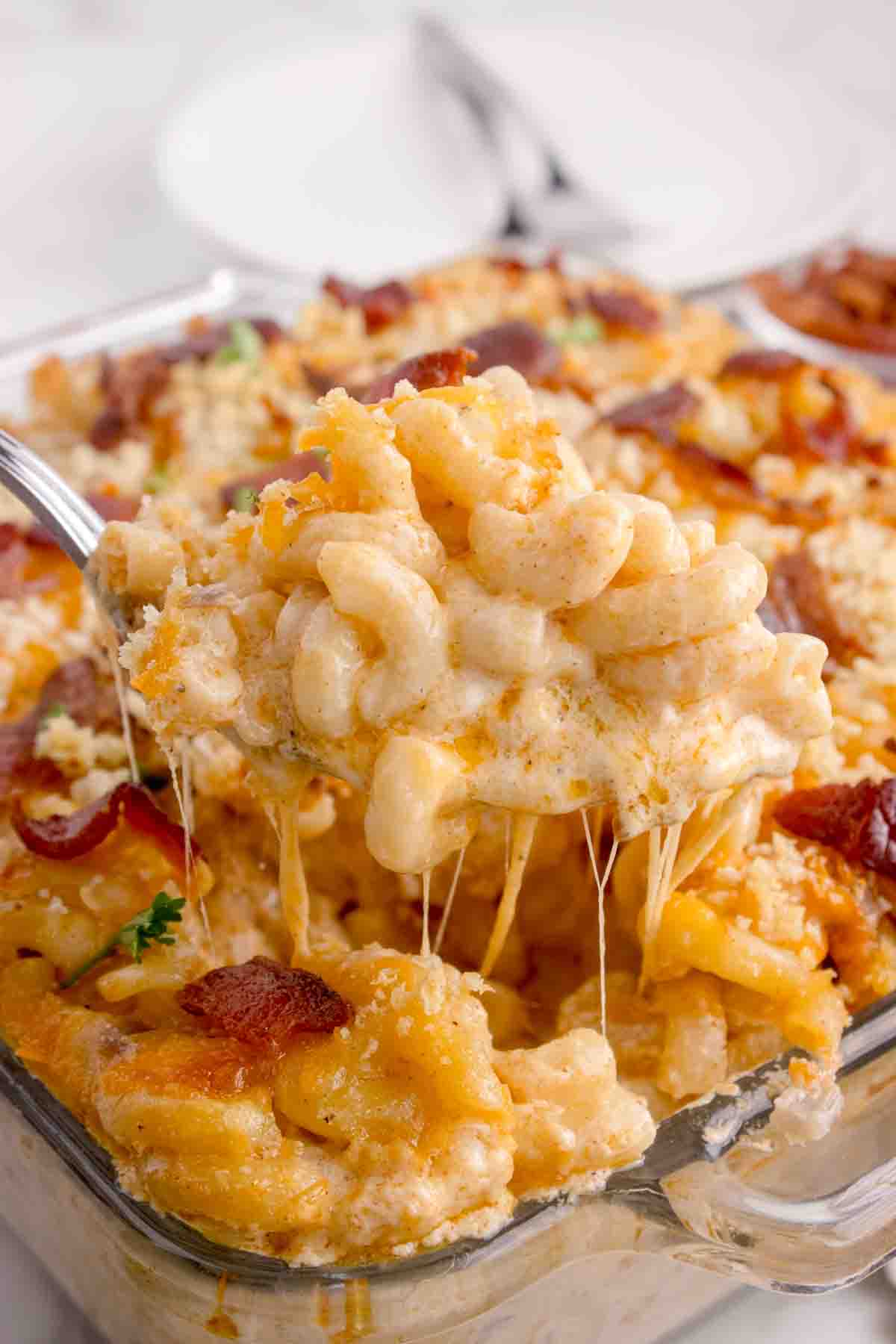 A spoonful of lobster mac and cheese being lifted out of the pan.