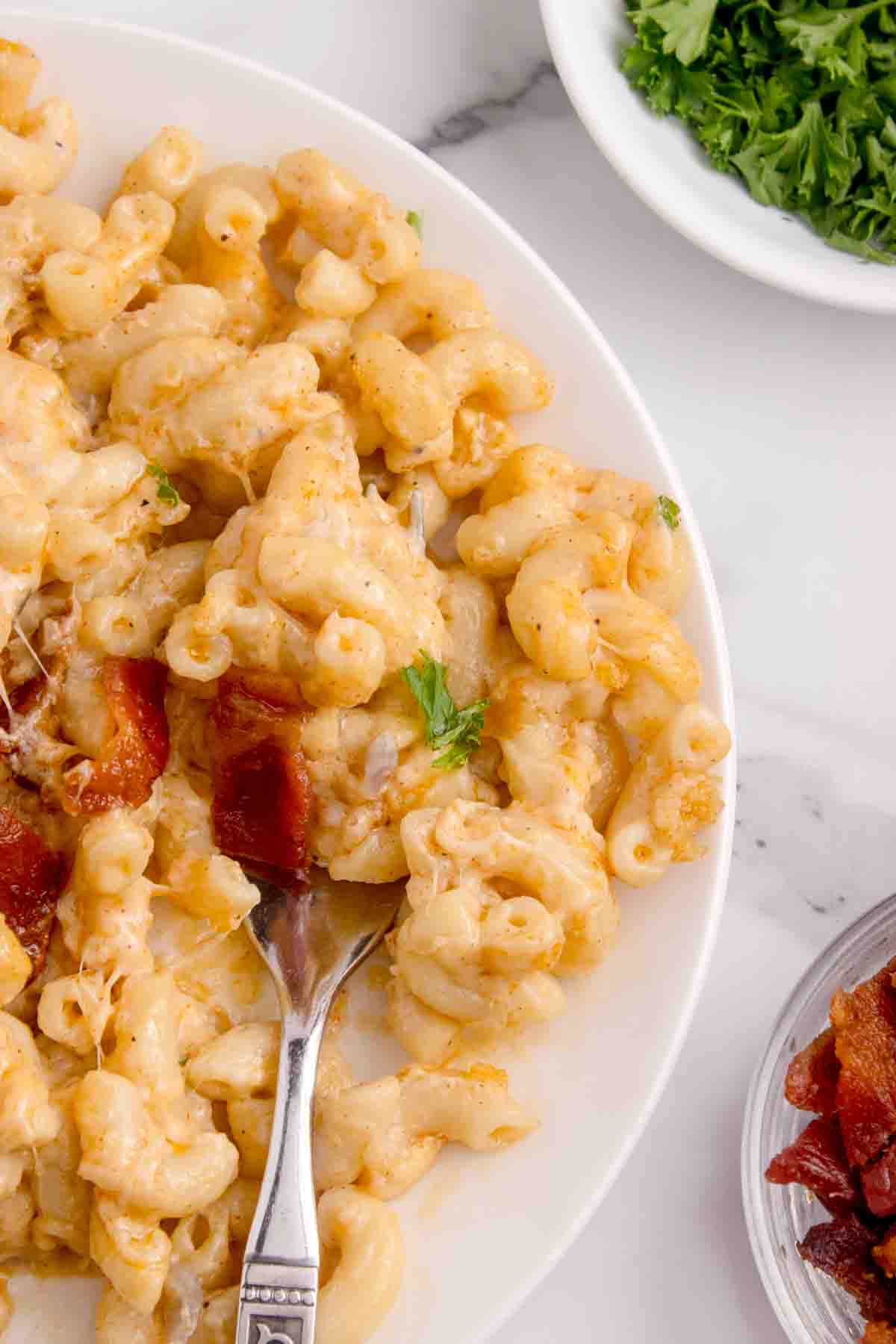 A close up image of a fork in a plate of lobster mac and cheese.