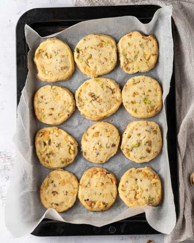 Overhead view of Pistachio Shortbread cookies on a parchment-lined baking tray.